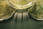 Three round clear glass plates filled with shimmering gold and green glitter, arranged in a close-up composition with light rays shining through the center.